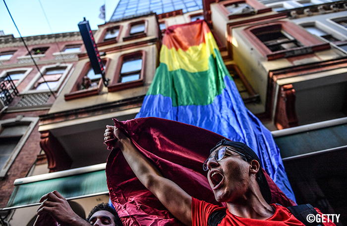 An activist below a Pride flag in Turkey