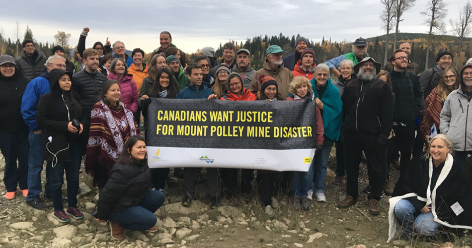 Group of people standing with sign reading "Canadians want justice for Mount Polley Mine Disaster"