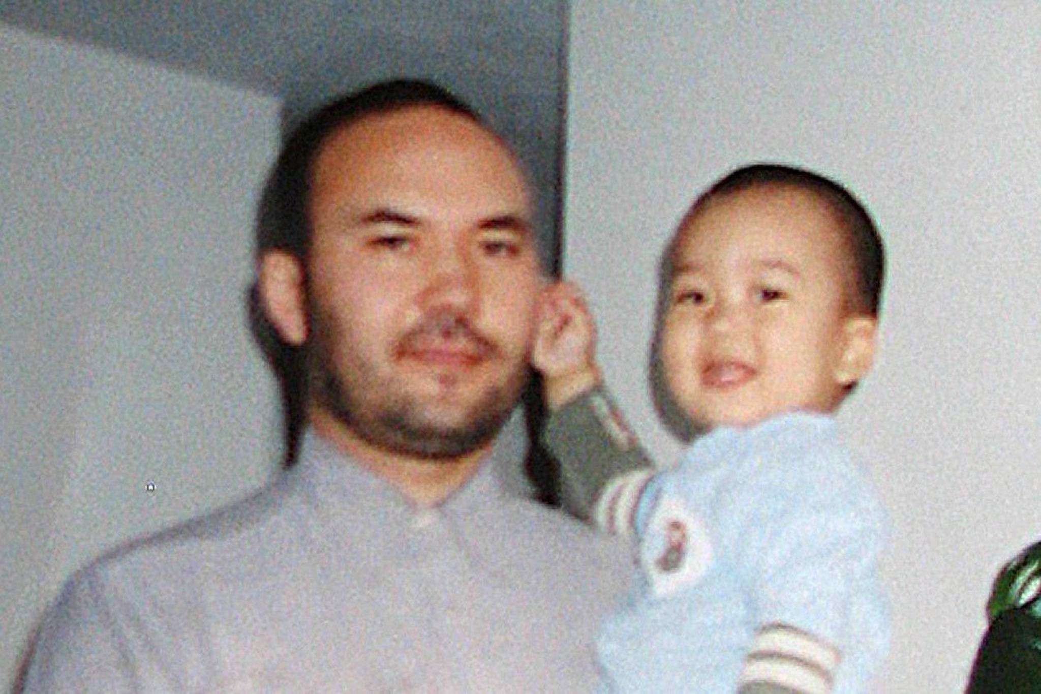 Huseyin Celil holding a baby in his arms