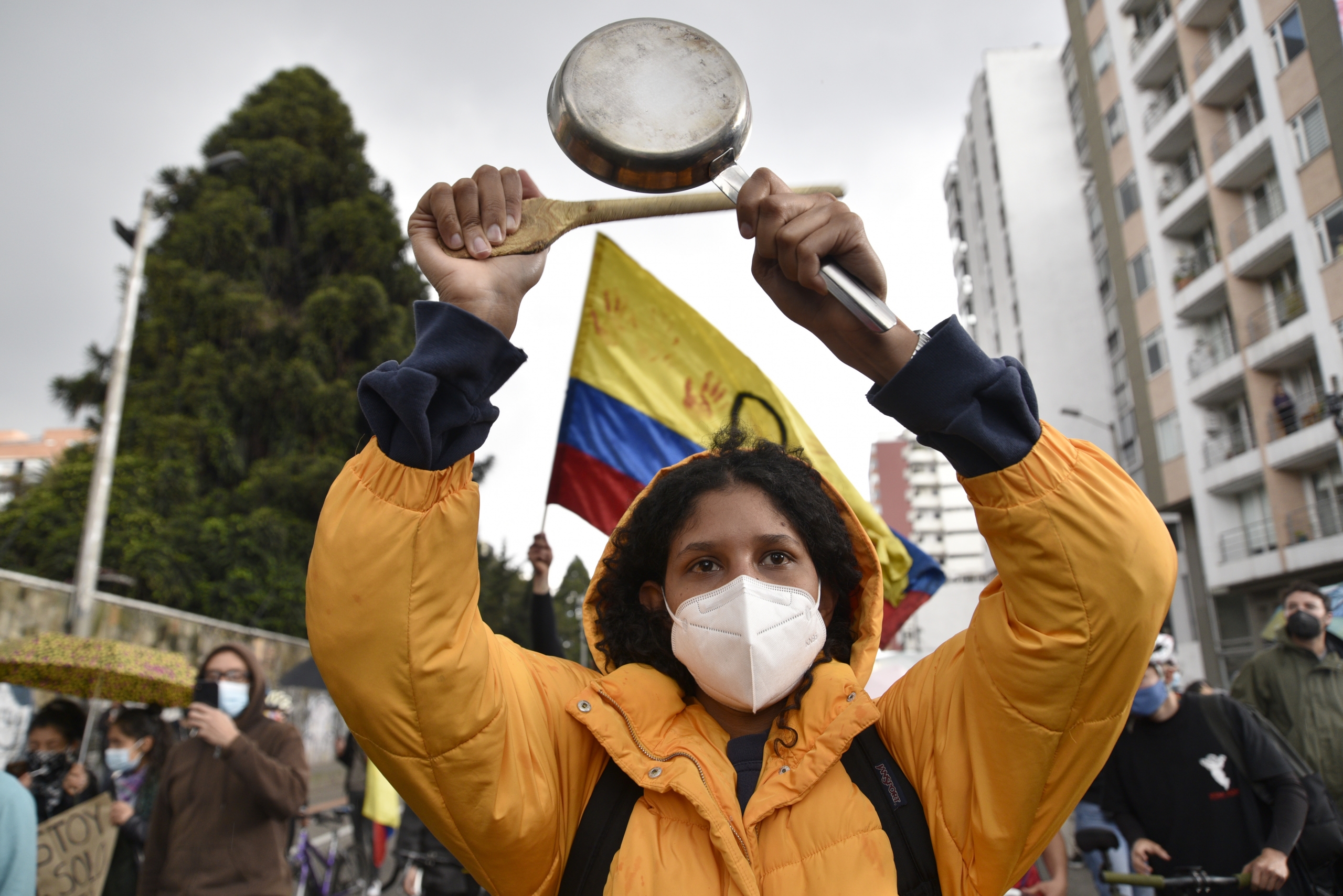 Woman at a protest holding up a pan and wooden spoon over her head