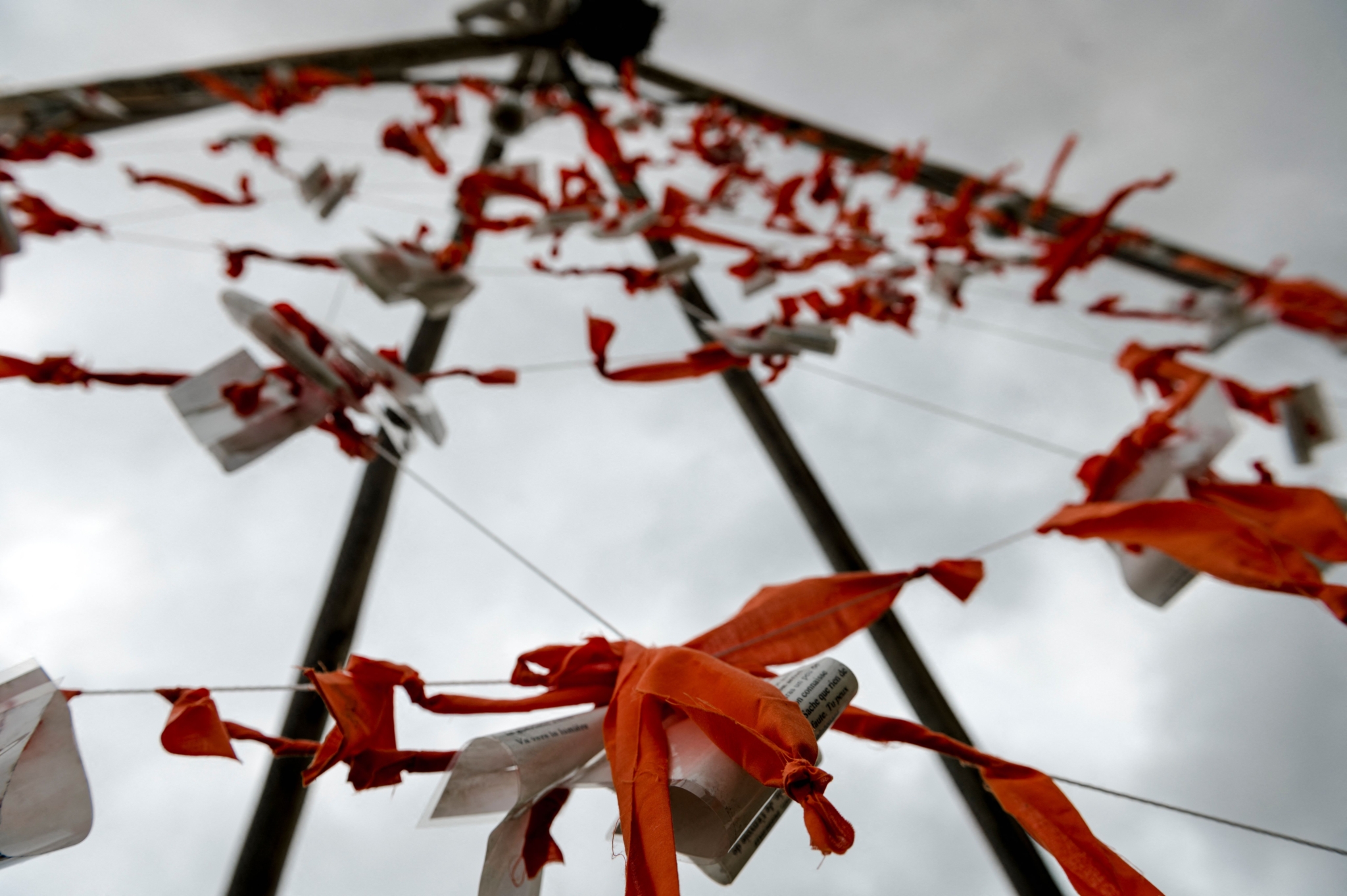 Notes and orange knots hang on a wooden tipi