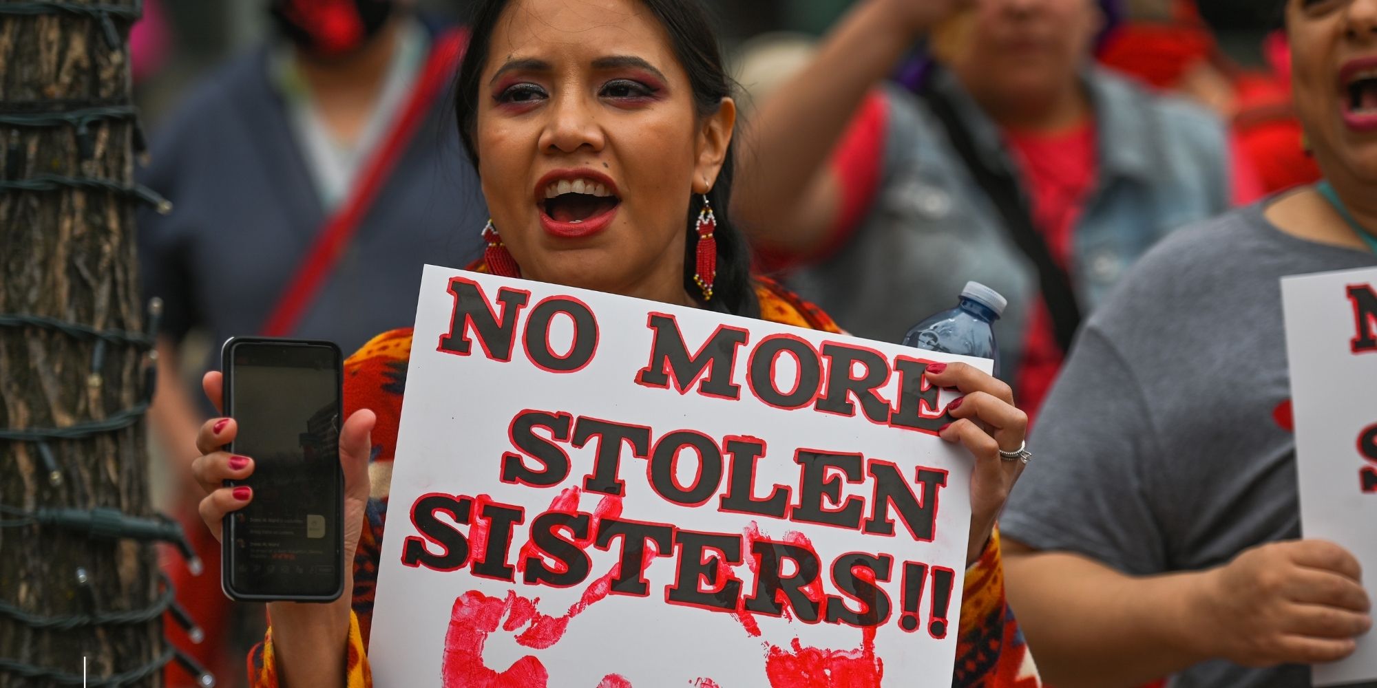 Woman holds up sign "No More Stolen Sisters"