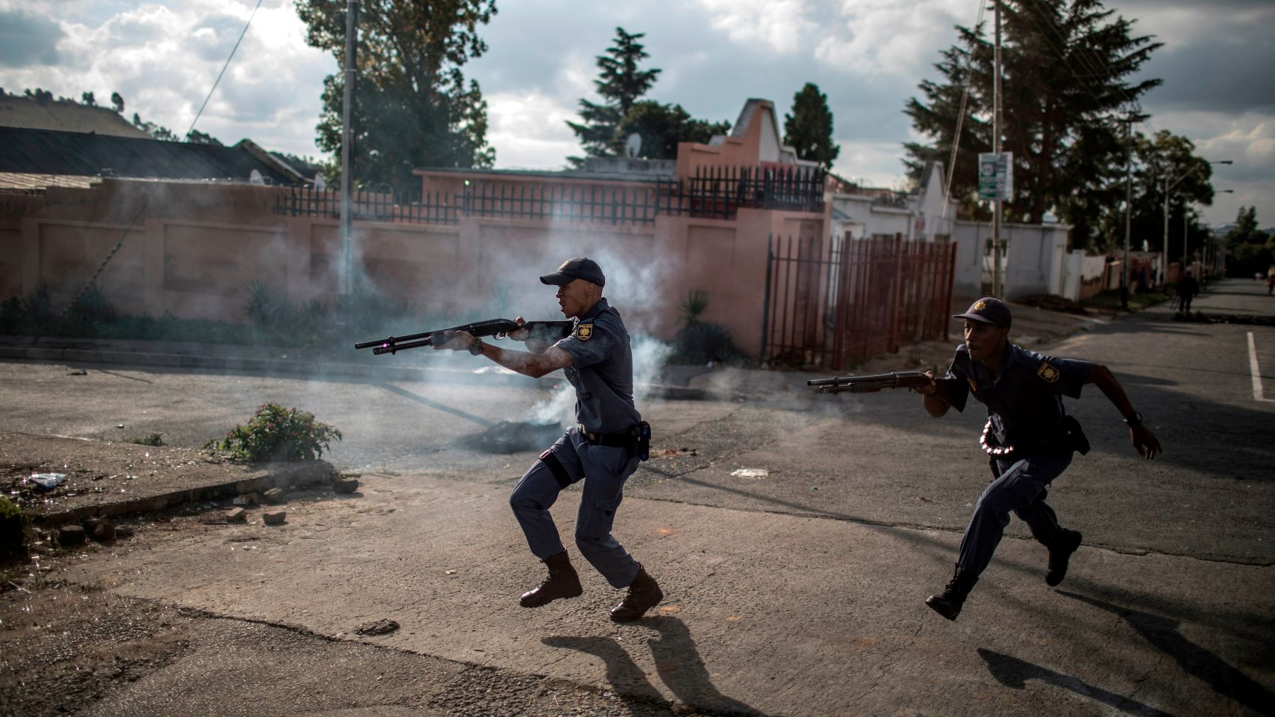 South African police officers fire rubber bullet as they chase protestors in the streets of Johannesburg, on April 23, 2019 during a protest against the lack of service delivery or basic necessities such as access to water and electricity, housing difficulties and lack of public road maintenance.