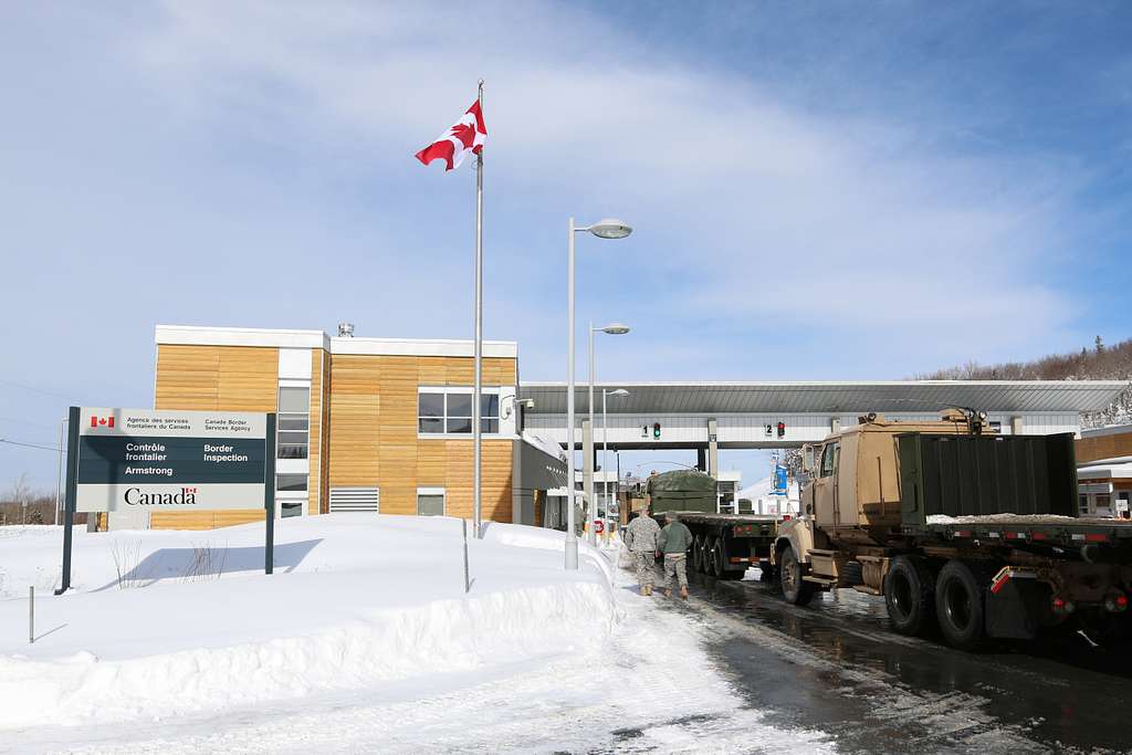 US Army Reserve trucks cross under an overhang at the Canadian border in winter.