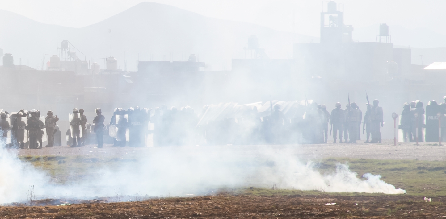 In Peru, a line on police officials in Peru hold weapons behind a haze of smoke, tear gas or another crowd-control agent.