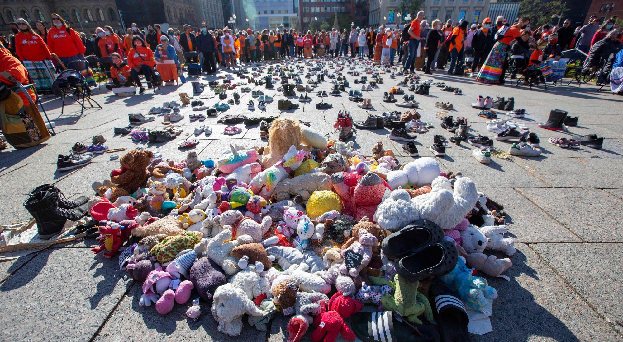 People stand around shoes that honor all the missing indigenous children during the first National Day for Truth and Reconciliation, on Parliament Hill in Ottawa on September 30, 2021. (Photo by Lars Hagberg / AFP) (Photo by LARS HAGBERG/AFP via Getty Images)