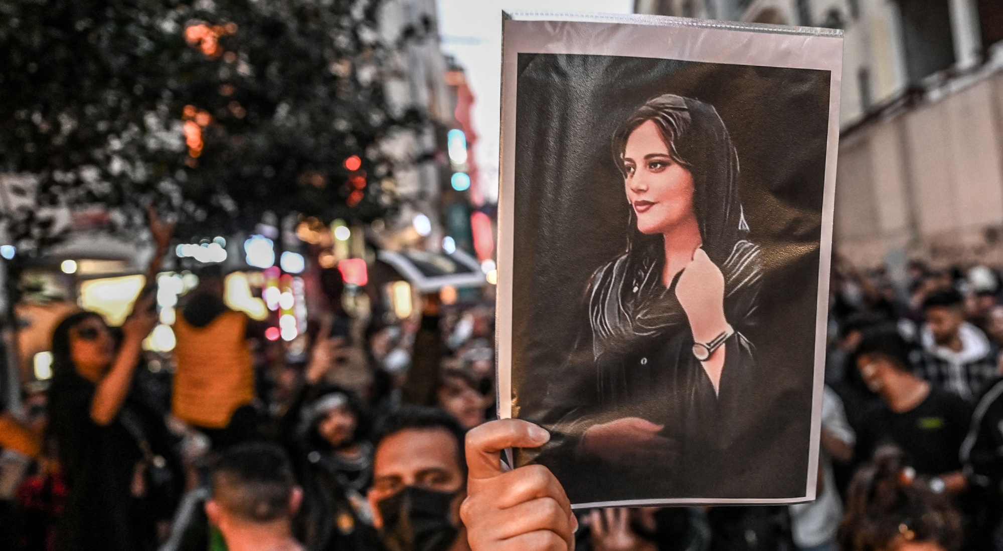 Protester in Iran holds up a photo of Mahsa Amini