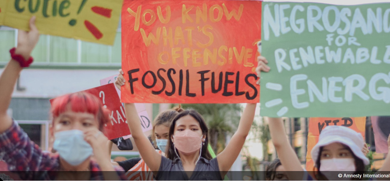 A woman holds a sign that says: "You what's offensive: Fossil Fuels"