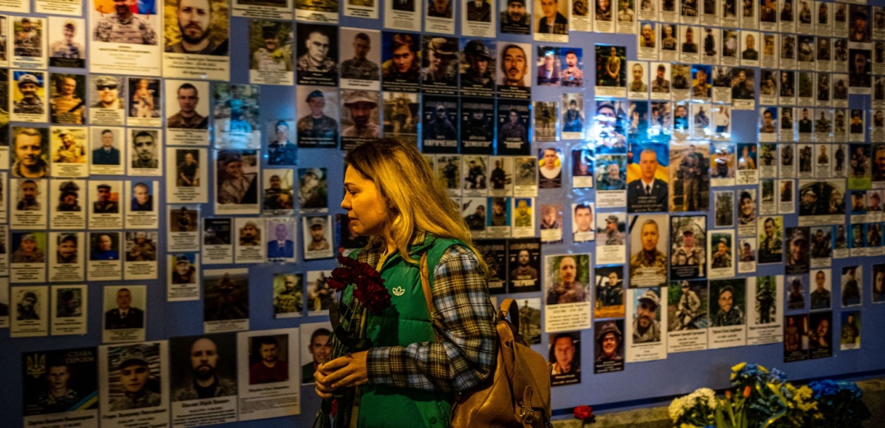 A woman reacts in front of pictures displayed at a Memory Wall of Fallen Defenders of Ukraine during the Russian invasion of Ukraine in Kyiv on February 24, 2023 on the first anniversary of the war. Photo by DIMITAR DILKOFF/AFP via Getty Images.