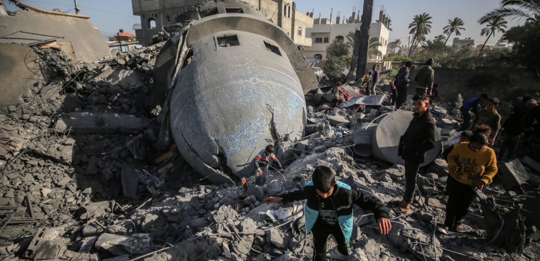 Palestinian children are walking past the rubble of the al-Bukhari mosque in Deir al-Balah, central Gaza Strip, on March 2, 2024, following an overnight Israeli air strike amid continuing battles between Israel and the Palestinian militant group Hamas. Photo by Majdi Fathi/NurPhoto via Getty Images.