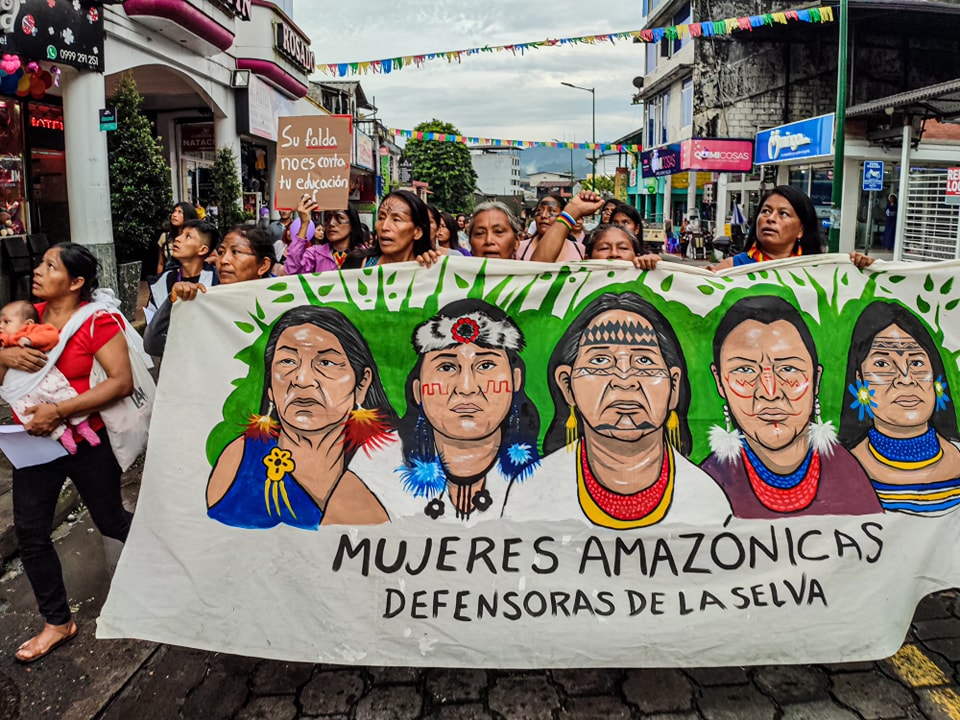 Amazonian women take part in a march holding a huge banner