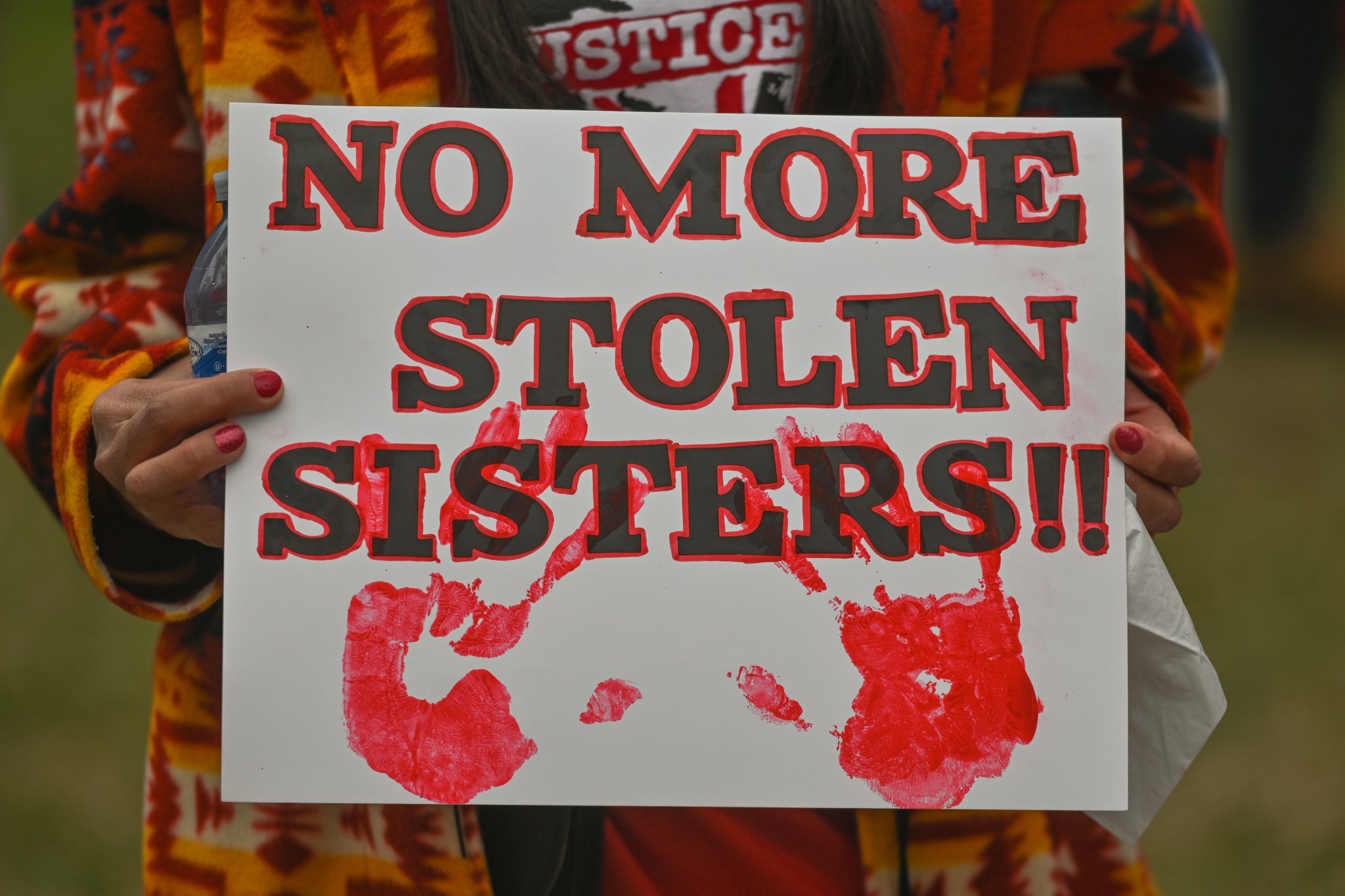 A participant holds a placard with words 'No More Stolen Sisters!!'.