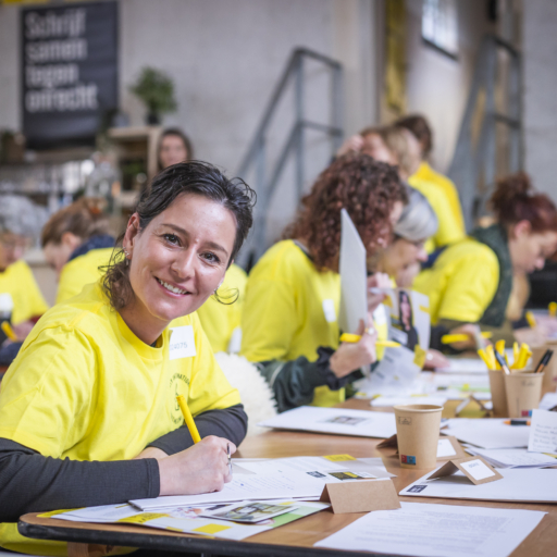 Group of people at a write for rights event writing, one women smiling as camera