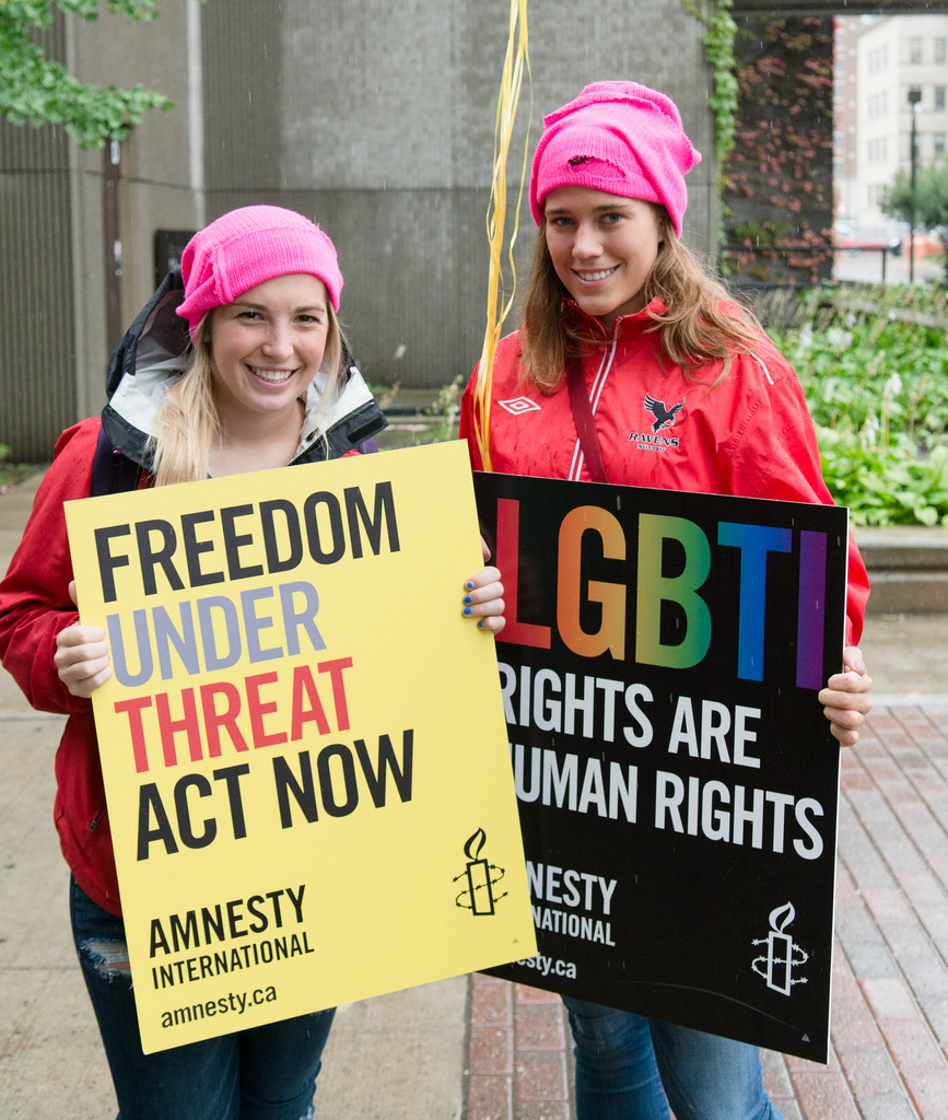 Two women hold up signs reading "Freedom under treat act now" and "LGBTI rights are human rights"