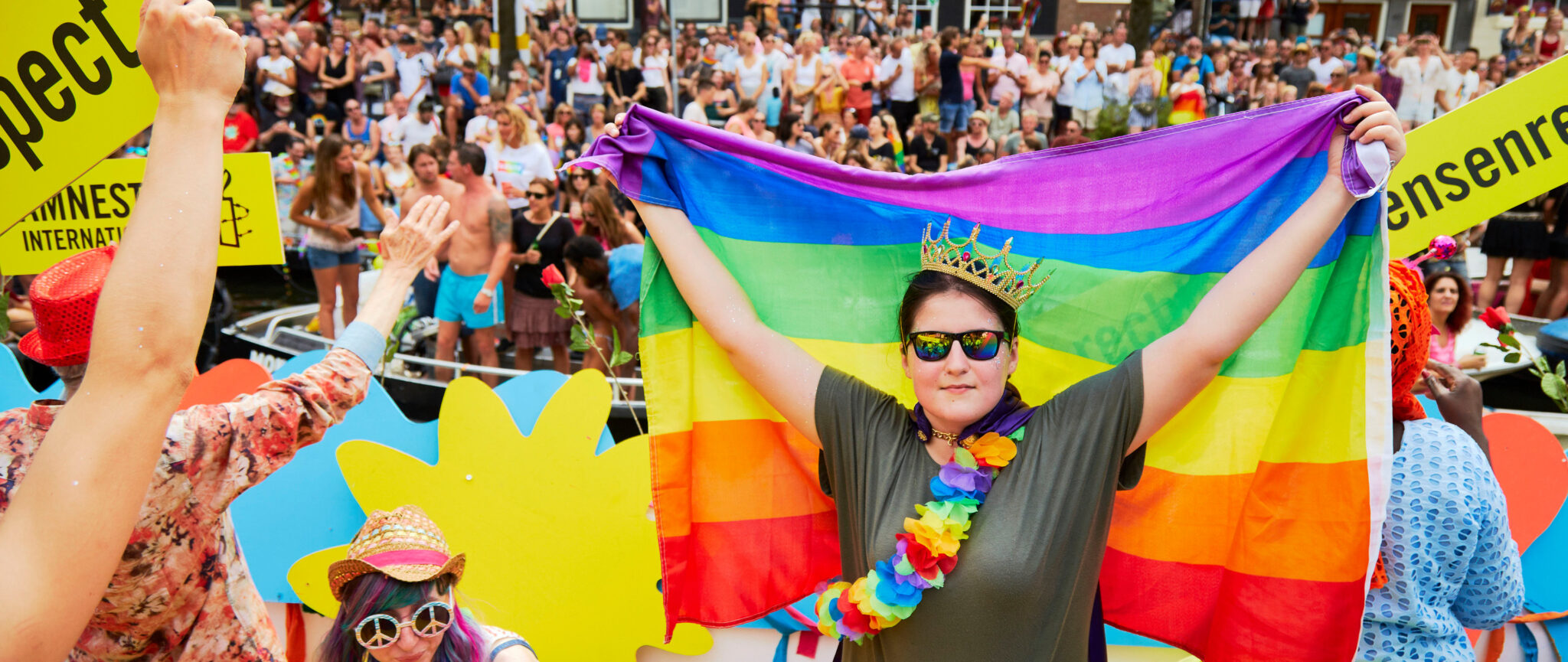 A woman holding up a pride flag at a pride parade
