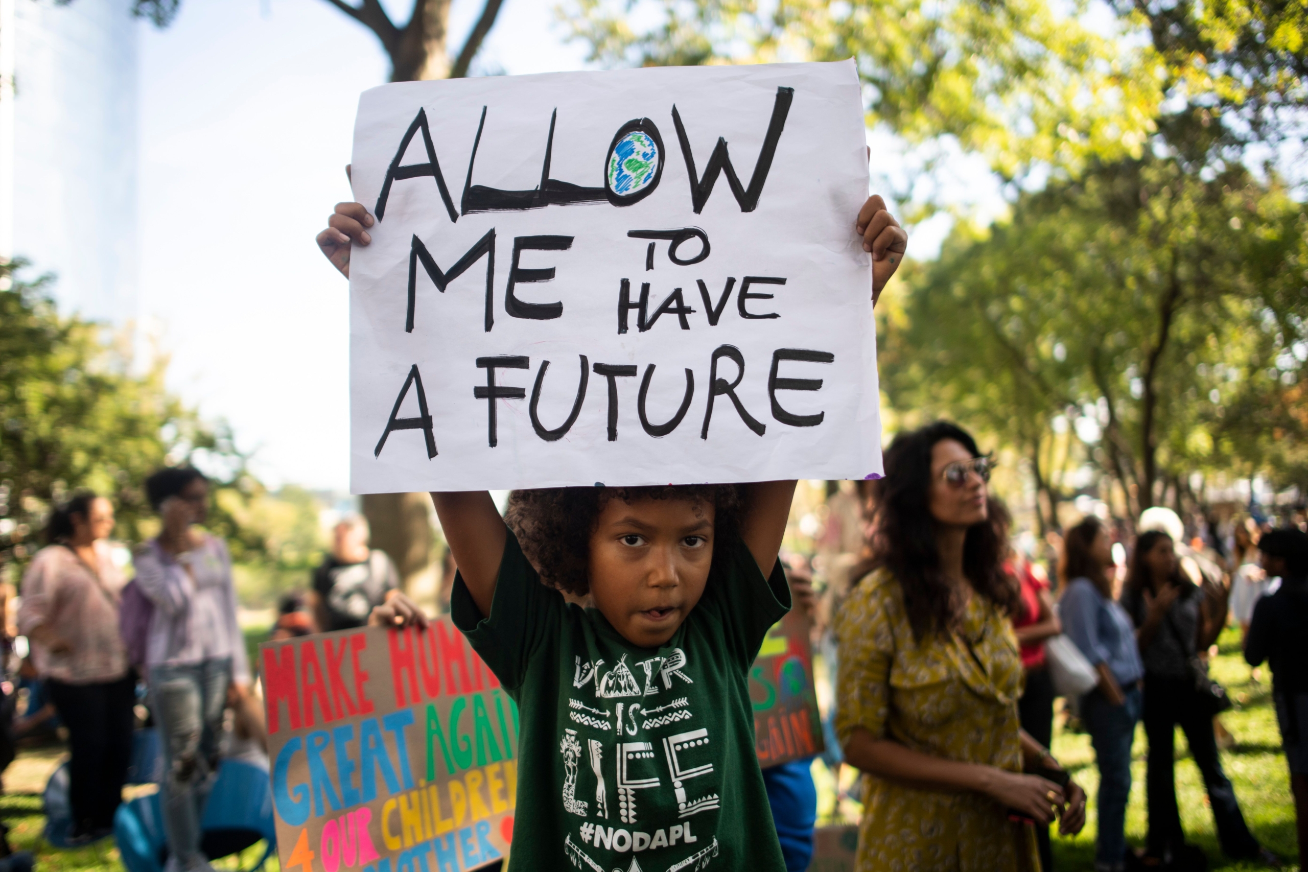 Child holding up sign reading Allow me to have a Future