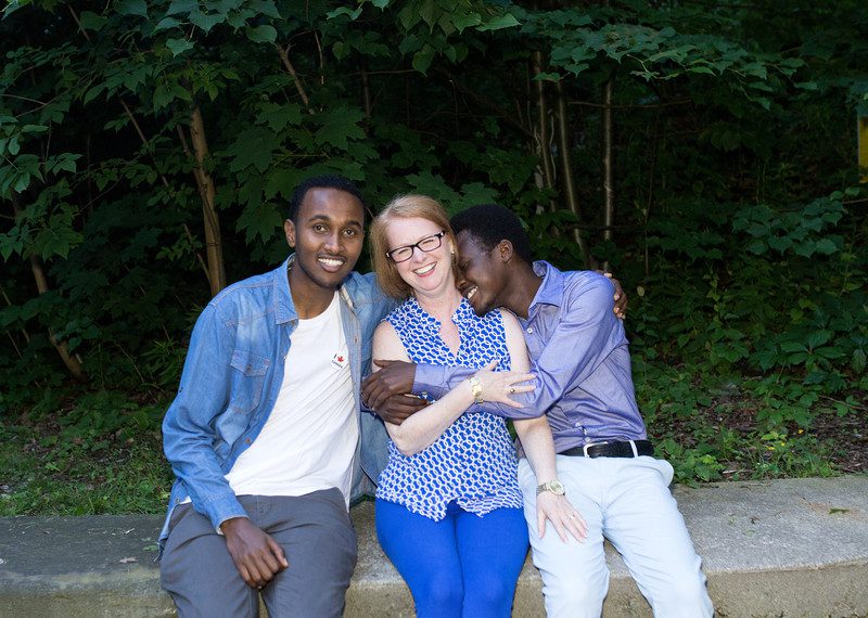 2 men on either side of a woman hugging and smiling