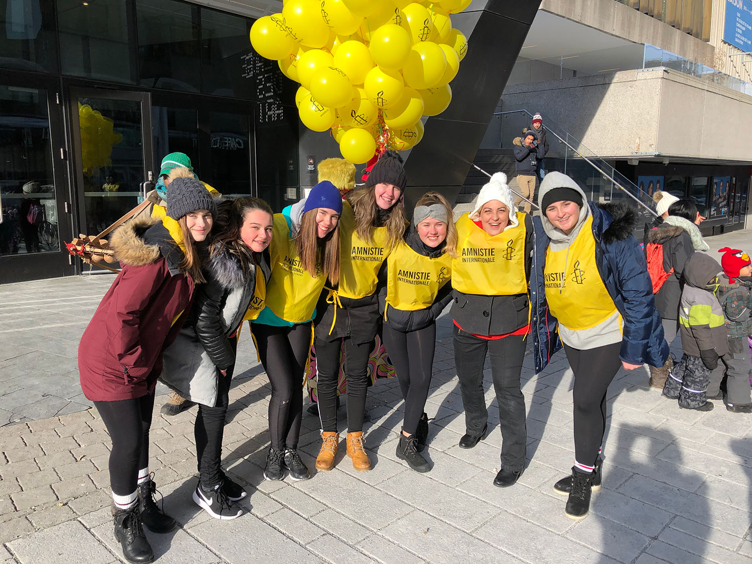A group of Amnesty youth volunteers huddled together with Amnesty balloons behind them