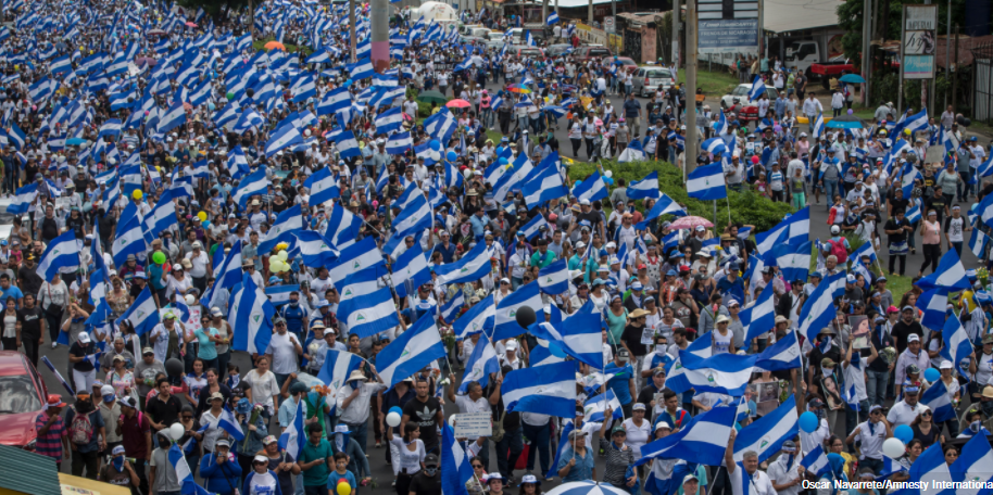 Hundreds of people marching in the streets with Nicaraguan flags.