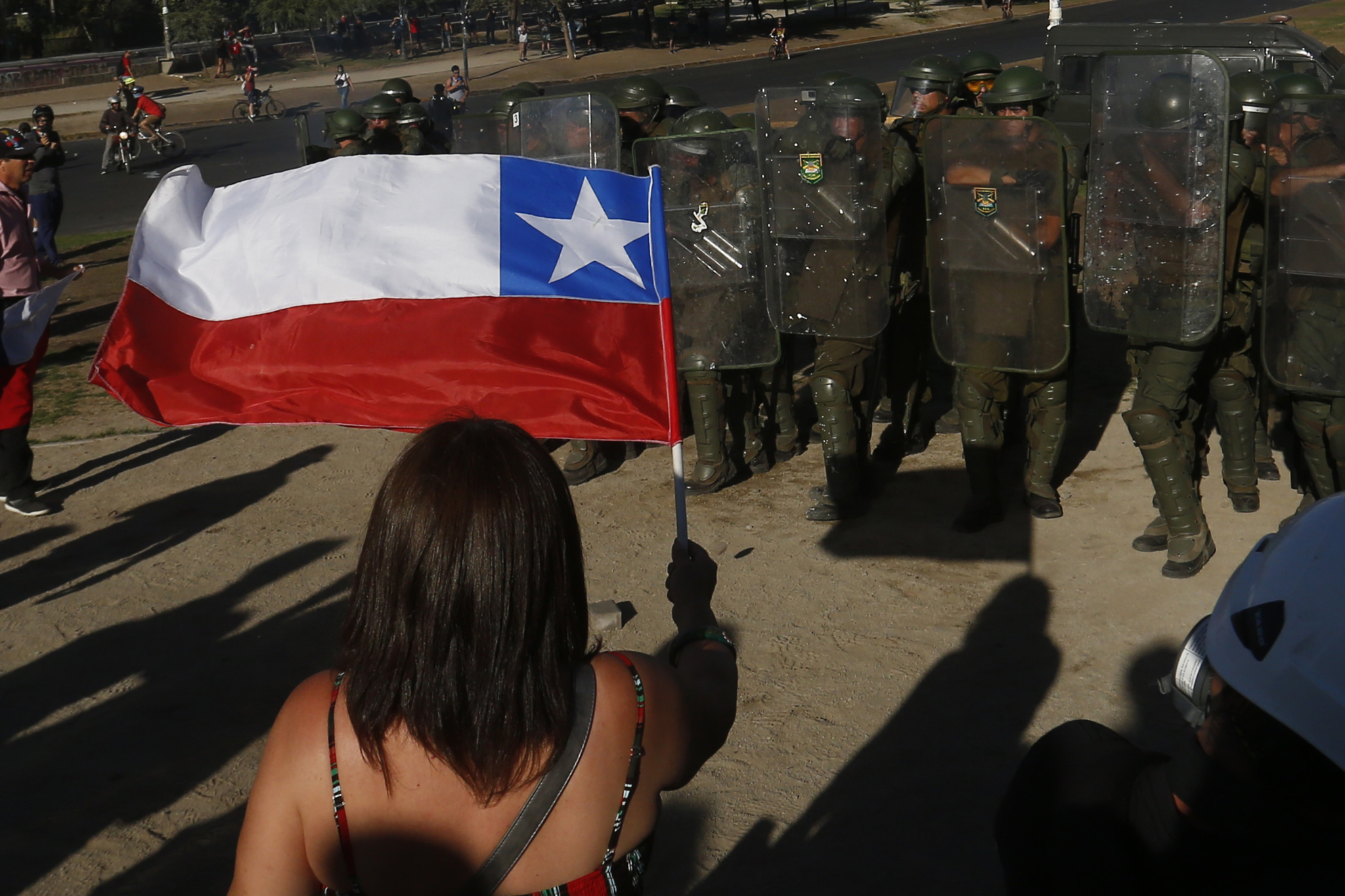 A protestor holds a Chilean flag in front of armed police