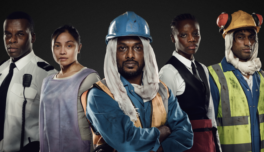 From left to right: A security guard, cleaner, construction working, waiter, and another construction worker pose shoulder to shoulder facing the camera.