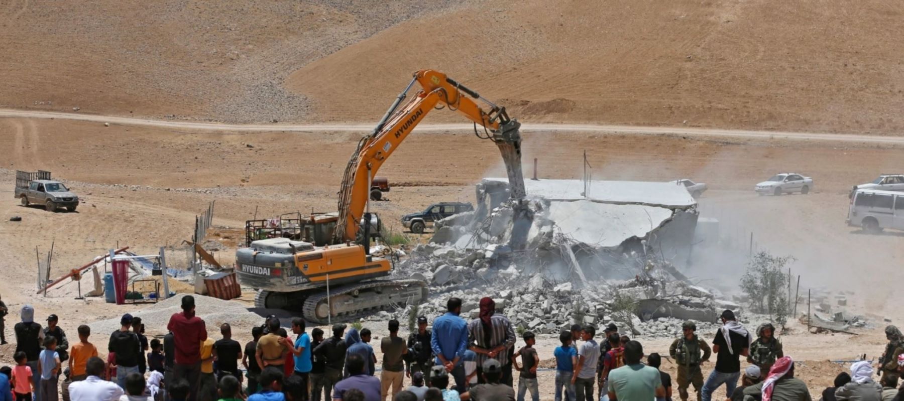 Residents watch as an Israeli bulldozer demolishes a Palestinian house in the Umm Qasas area of Masafer Yatta in the occupied West Bank on July 25, 2022. (Photo by MOSAB SHAWER / AFP) (Photo by MOSAB SHAWER/AFP via Getty Images)