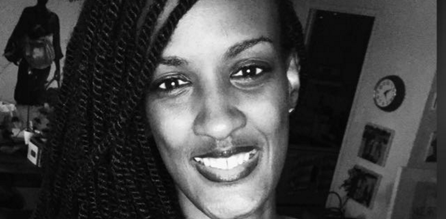 A black-and-white headshot of a smiling woman with dark skin and long braids