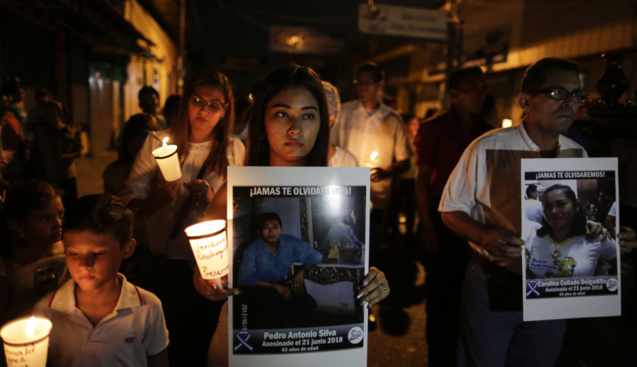 A young woman, a boy and a middle-aged man are among people participating in a candelight vigil in memory of a man who was killed in a protest in Nicaragua.