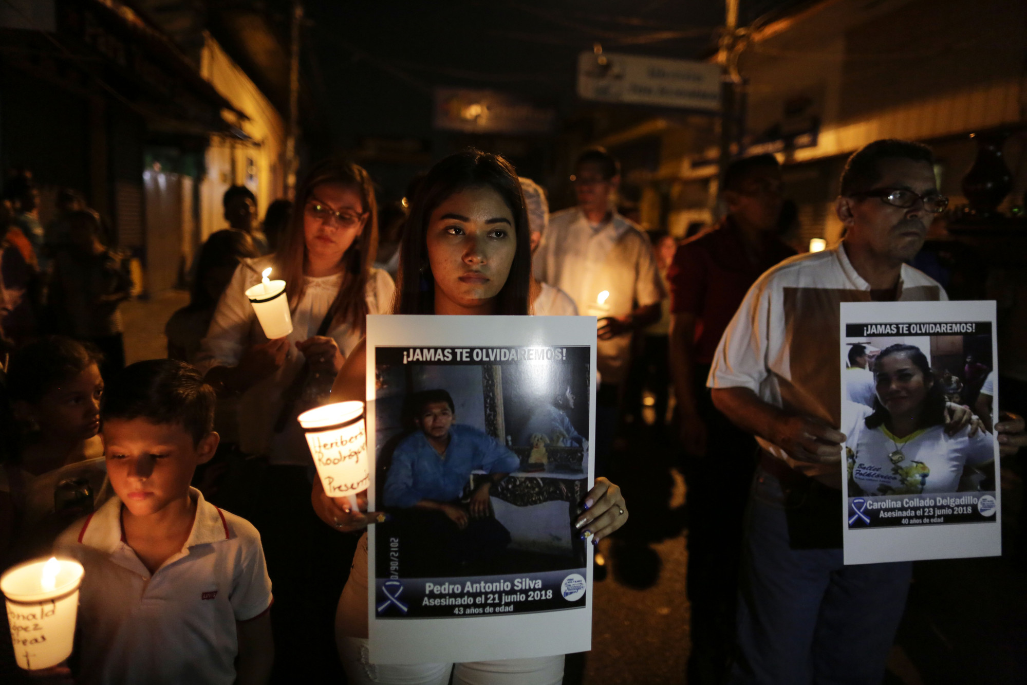 A young woman, a boy and a middle-aged man are among people participating in a candelight vigil in memory of a man who was killed in a protest in Nicaragua.