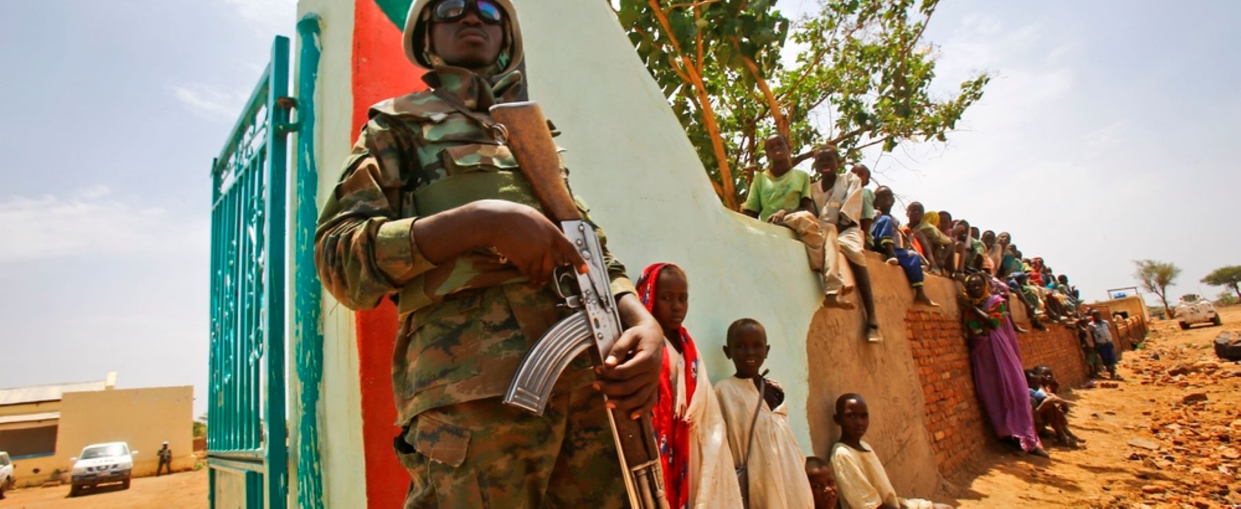 A UN peacekeeper stands guard as crowds of children and villagers gather to welcome Steven Koutsis (unseen), the United States' top envoy in Sudan, in the war-torn town of Golo in the thickly forested mountainous area of Jebel Marra in central Darfur on June 19, 2017.