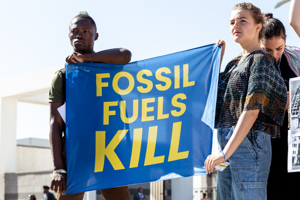 Protesters hold a banner that says: FOSSIL FUELS KILL