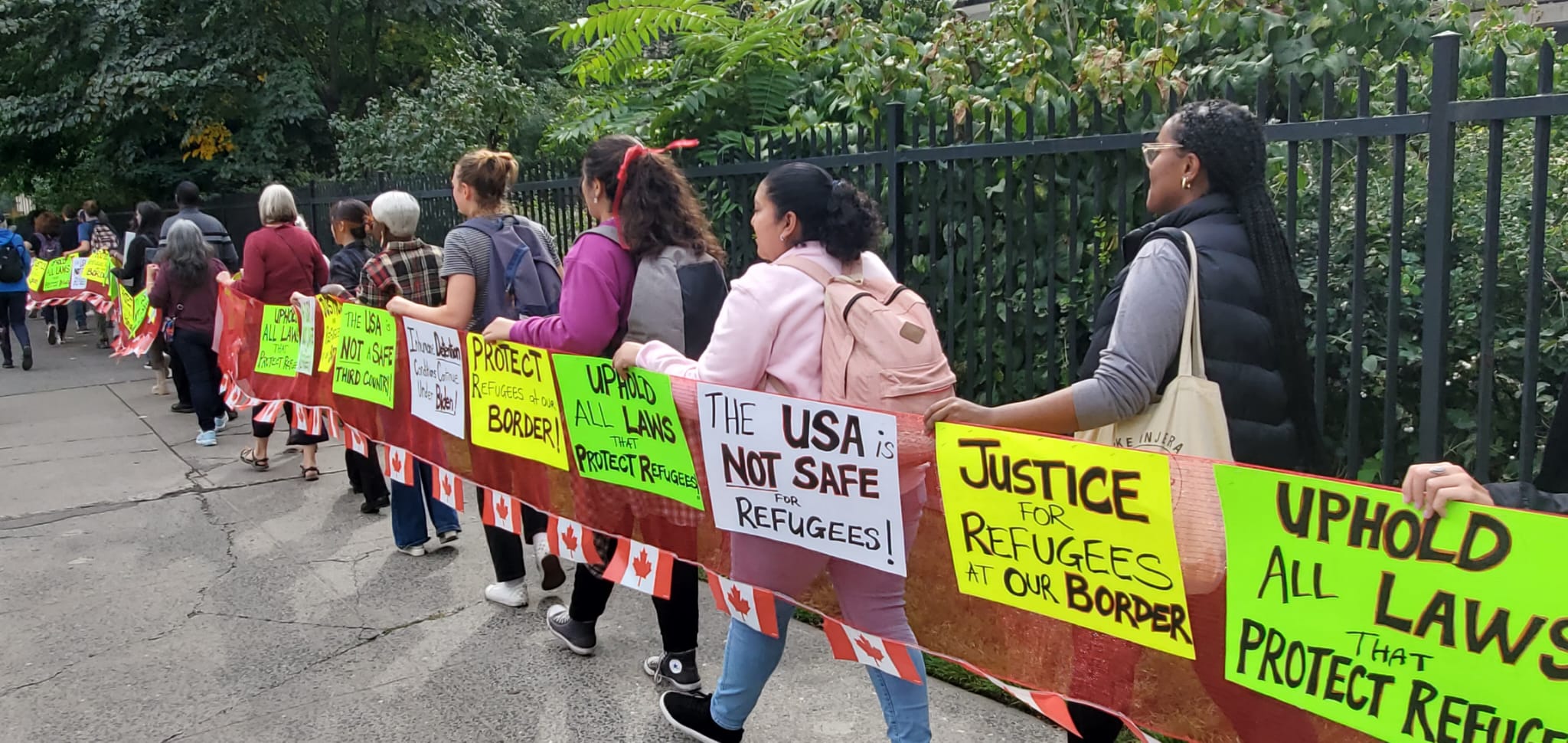 People hold signs at rally for refugee rights