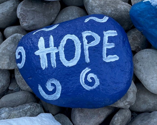 A stone painted blue bears the word "Hope"