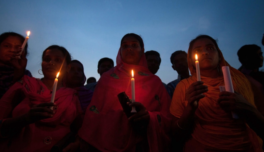 Bangladeshi garment workers and relatives of victims of the Rana Plaza building collapse hold candles during a memorial at the site of the Rana Plaza garment factory building collapse in Savar, on the outskirts of Dhaka on October 24, 2013, the six-month anniversary of the disaster. Relatives of the 1,135 people who lost their lives when the Rana Plaza complex collapsed on April 24 also said they had still to receive any compensation for their loss as they rallied at the site of the tragedy.