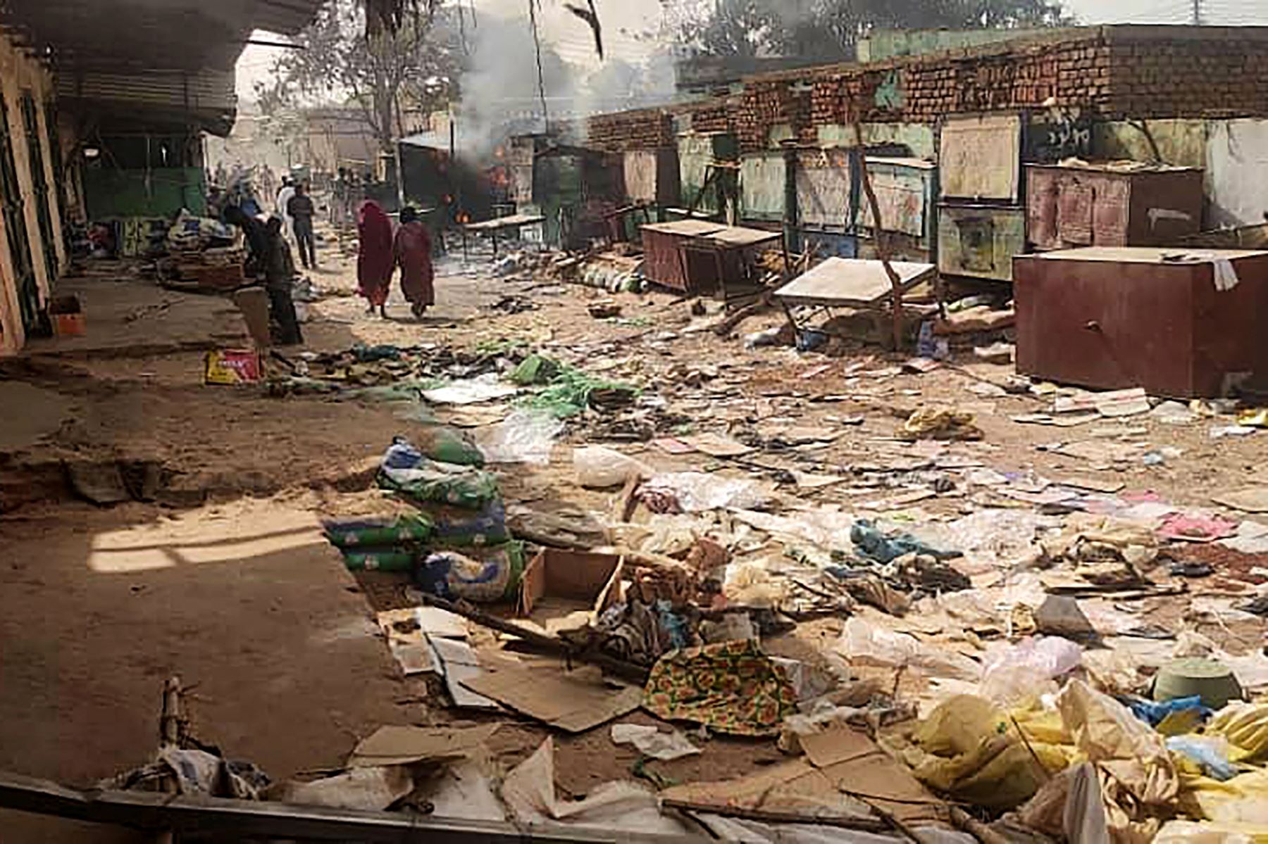People walk among scattered objects in the market of El Geneina, the capital of West Darfur, as fighting continues in Sudan between the forces of two rival generals, on April 29, 2023. - At least 96 people were reported to have been killed in El Geneina this week, the UN said, as fierce fighting between Sudan's army and paramilitaries entered a third week, violating a renewed truce. (Photo by -/AFP via Getty Images)