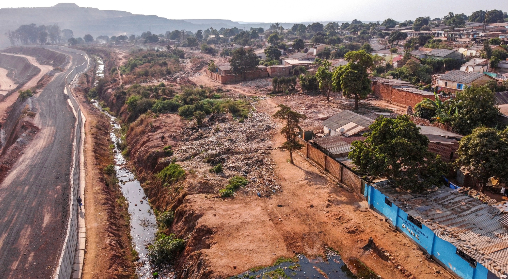 TOPSHOT - A general view of houses in the Gecamine district (General Society of Quarries and Mines of the DRC) on the edge of the abyss of the Chinese mining company COMMUS (Musonoïe Mining Company Global SAS), downtown Kolwezi on October 13, 2022. - Once a thriving neighbourhood of neat houses and tree-shaded avenues, this district of the city of Kolwezi is now nearly destroyed. Mutombo's house, surrounded by the rubble of demolished buildings, is one of the last hold-outs near the concrete barrier sealing off the open-pit mine. The Chinese-owned business wants to expand, and many nearby residents took buy-outs. (Photo by JUNIOR KANNAH/AFP via Getty Images)