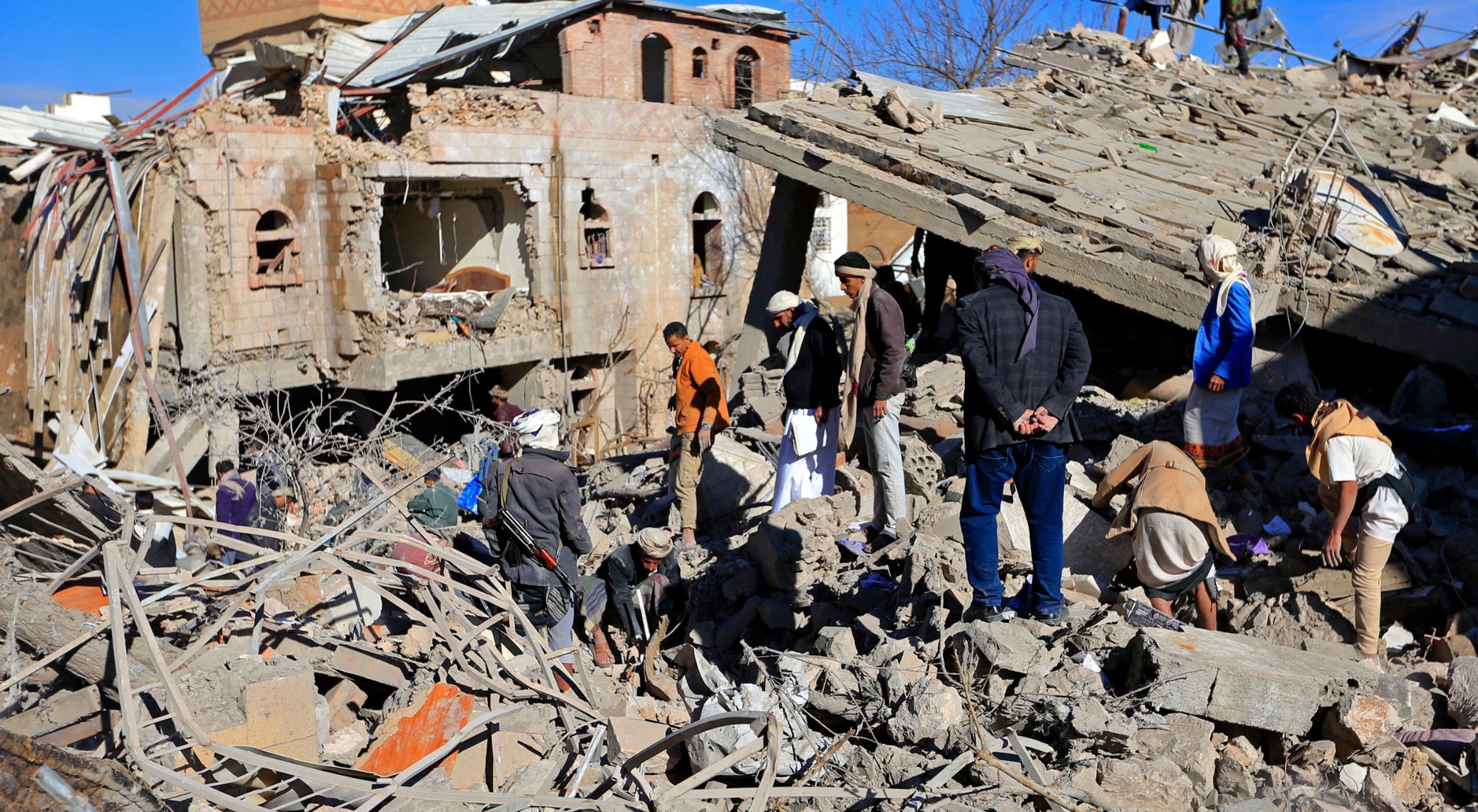Yemenis inspect the damage following overnight air strikes by the Saudi-led coalition targeting the Huthi rebel-held capital Sanaa, on January 18, 2022. - The Saudi and UAE-led coalition coalition fighting Yemen's Huthi insurgents said it had launched air strikes targeting the rebel-held capital Sanaa after a deadly attack against coalition ally Abu Dhabi. (Photo by Mohammed Huwais/AFP via Getty Images)