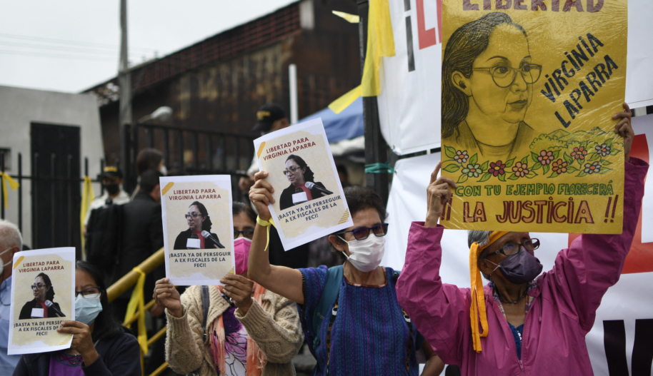 Protestors in Guatemala hold signs denouncing criminalization of prosecutors and human rights defenders