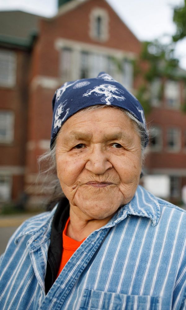 Kamloops Indian Residential School survivor Evelyn Camille, 82, poses for a pictures next to a makeshift memorial at the former Kamloops Indian Residential School to honour the 215 children whose remains have been discovered buried near the facility, in Kamloops, British Columbia, Canada, on June 4, 2021. - Canadian Prime Minister Justin Trudeau on June 4 urged the Catholic Church to "take responsibility" and release records on indigenous residential schools under its direction, after the discovery of remains of 215 children in unmarked graves. (Photo by Cole Burston / AFP) (Photo by COLE BURSTON/AFP via Getty Images)