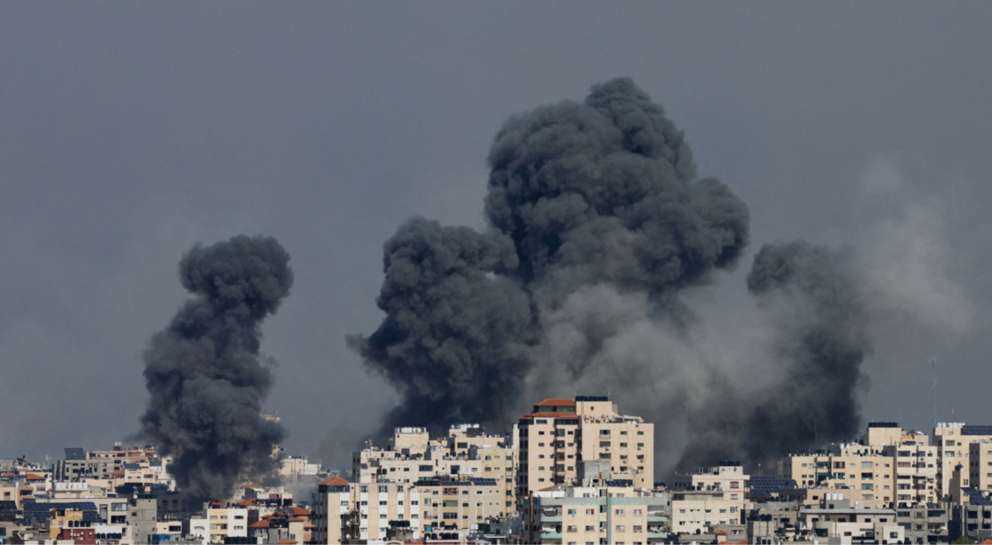 Clouds of smoke billow toward the sky above cream-coloured apartment buildings.