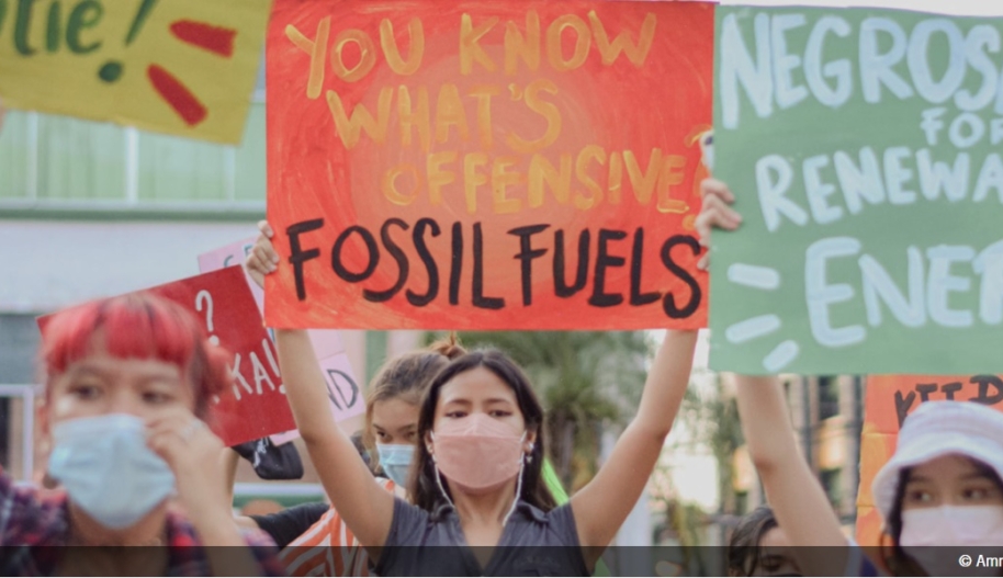 A woman holds a sign that says: "You what's offensive: Fossil Fuels"