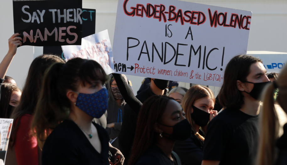 Women protest holding signs that read "Gender-Based Violence is a Pandemic" and "Say Their Names"