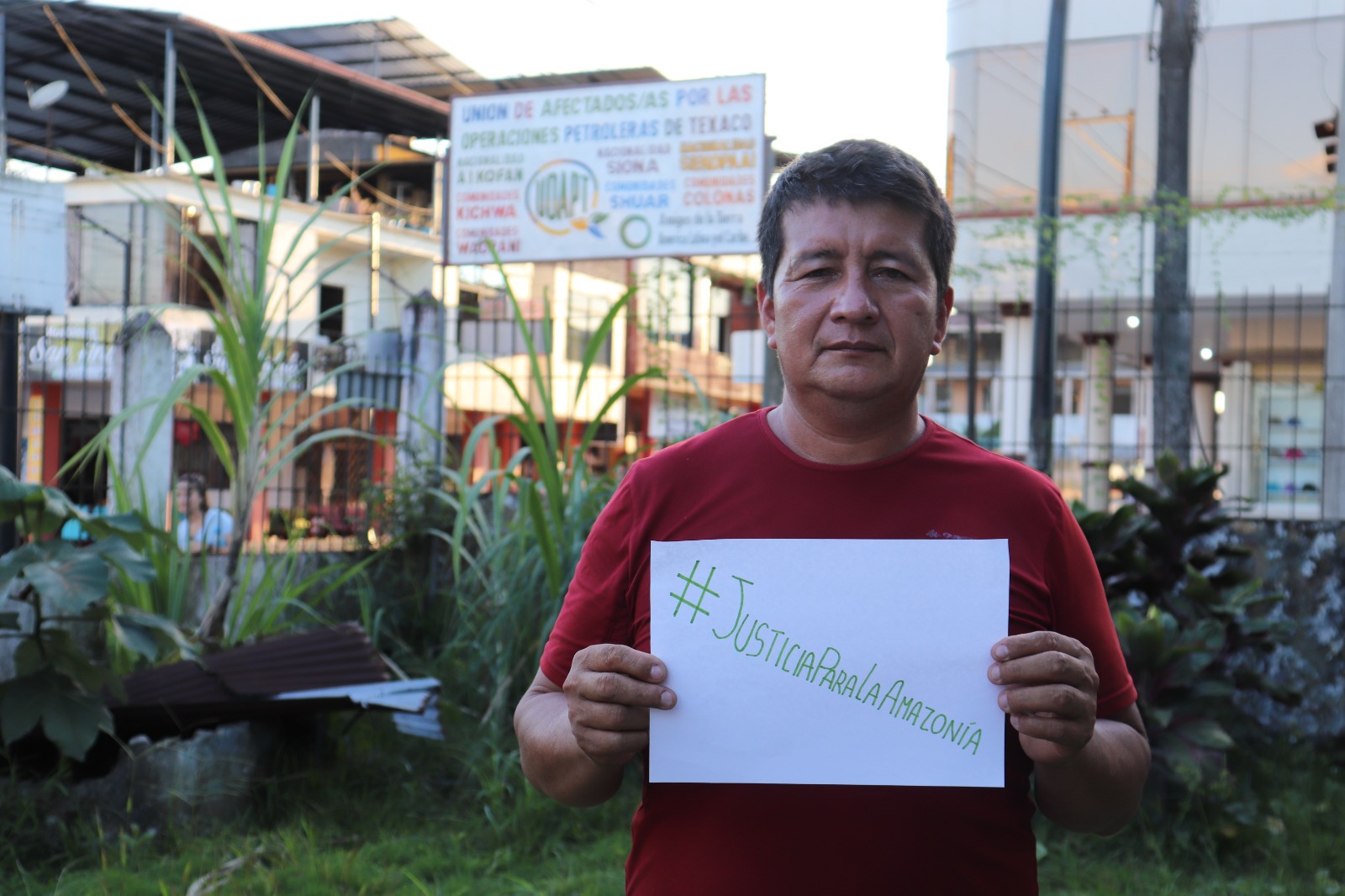 An environment defender holds a sign that says Justice for the Amazon