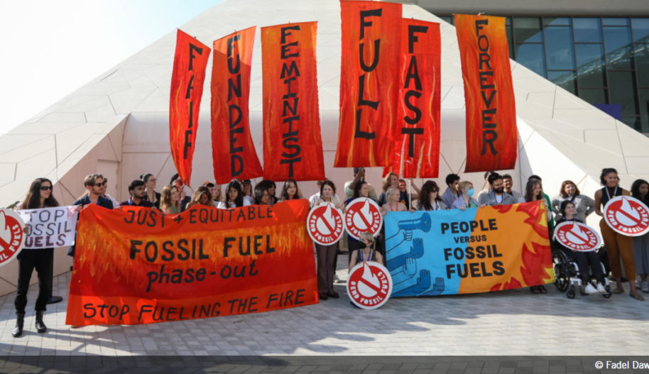 People at COP28 hold signs calling for phase out of fossil fuels