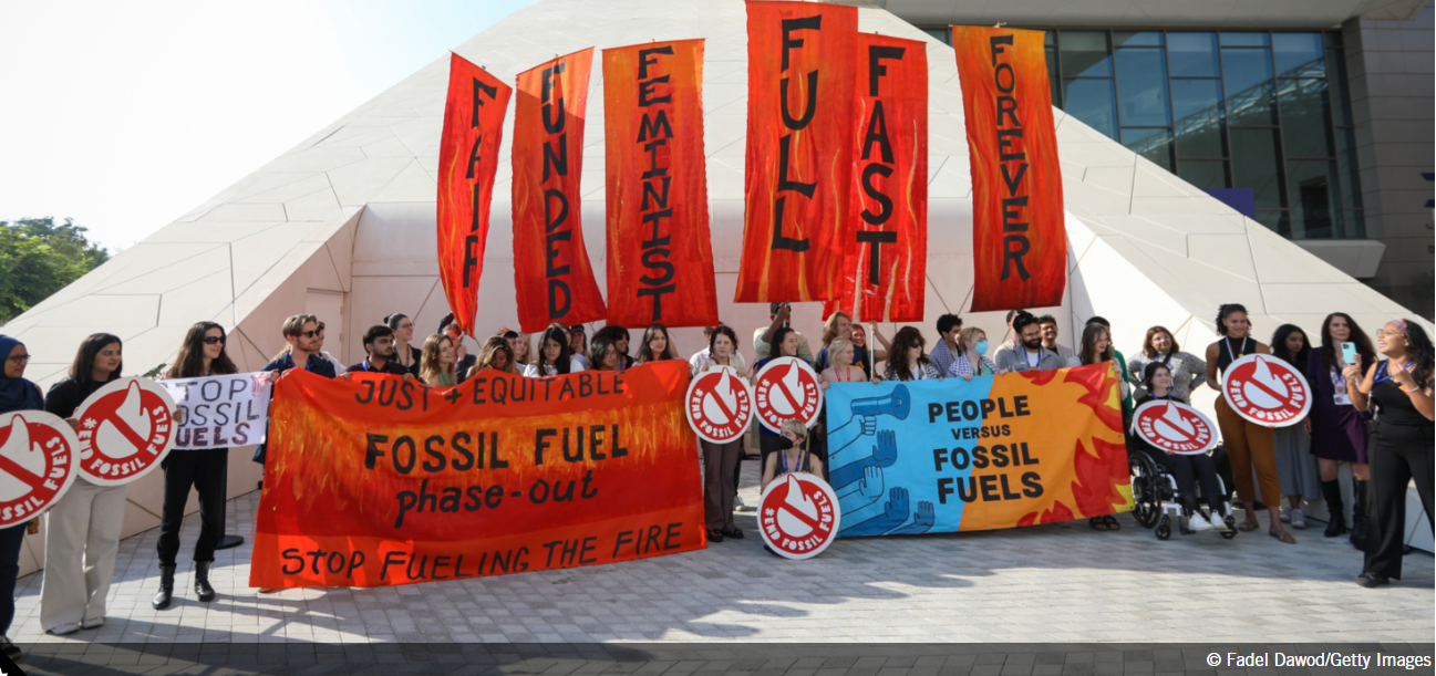 People at COP28 hold signs calling for phase out of fossil fuels