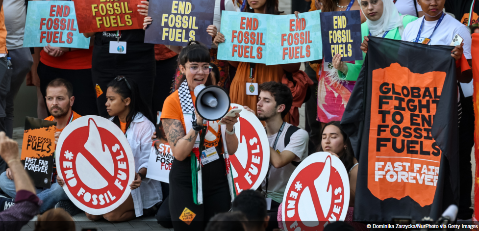 People at COP hold signs that say End Fossil Fuels