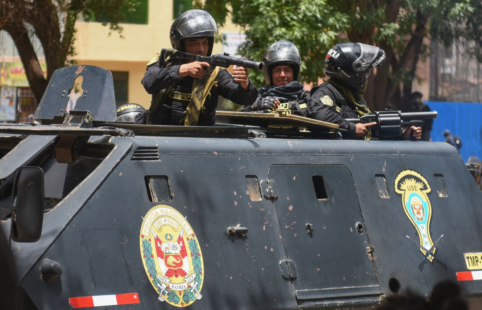 security forces point weapons from an armoured vehicle