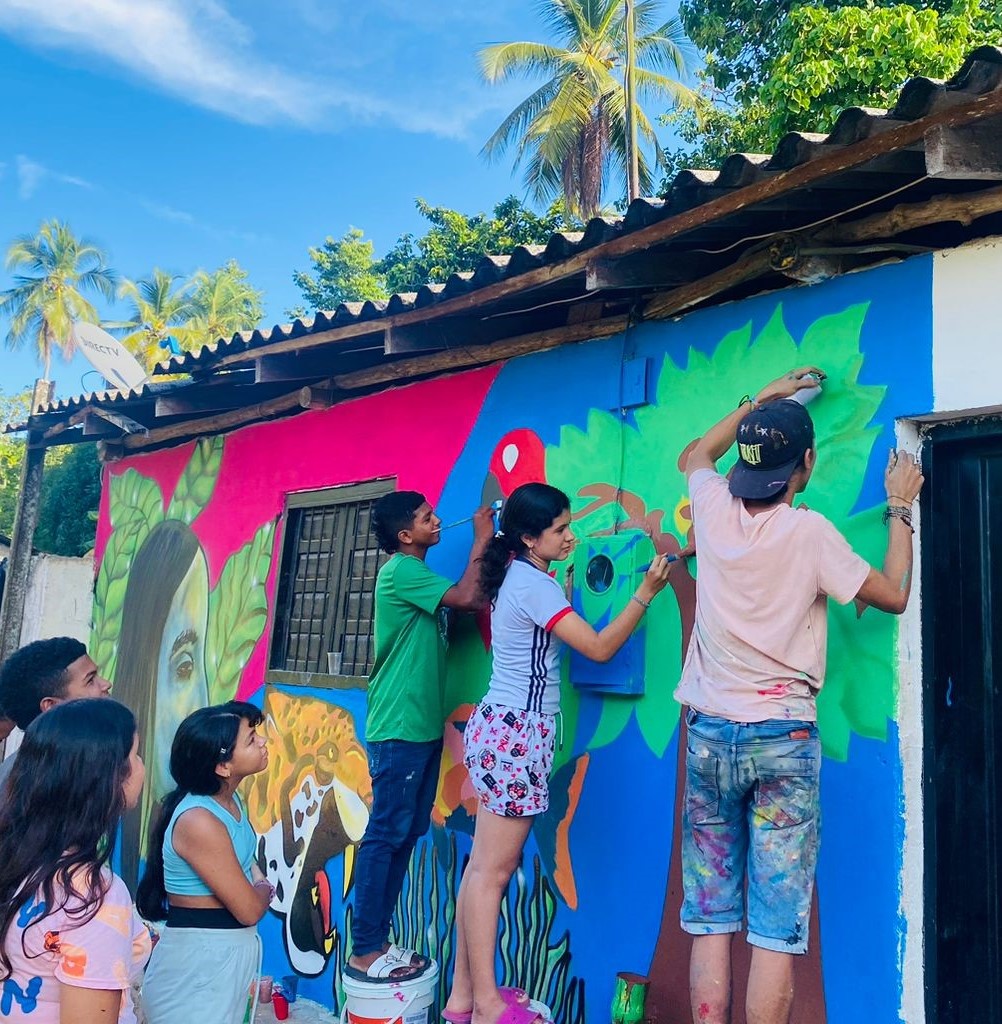 Youth paint a beautiful mural of nature on the outside wall of a house