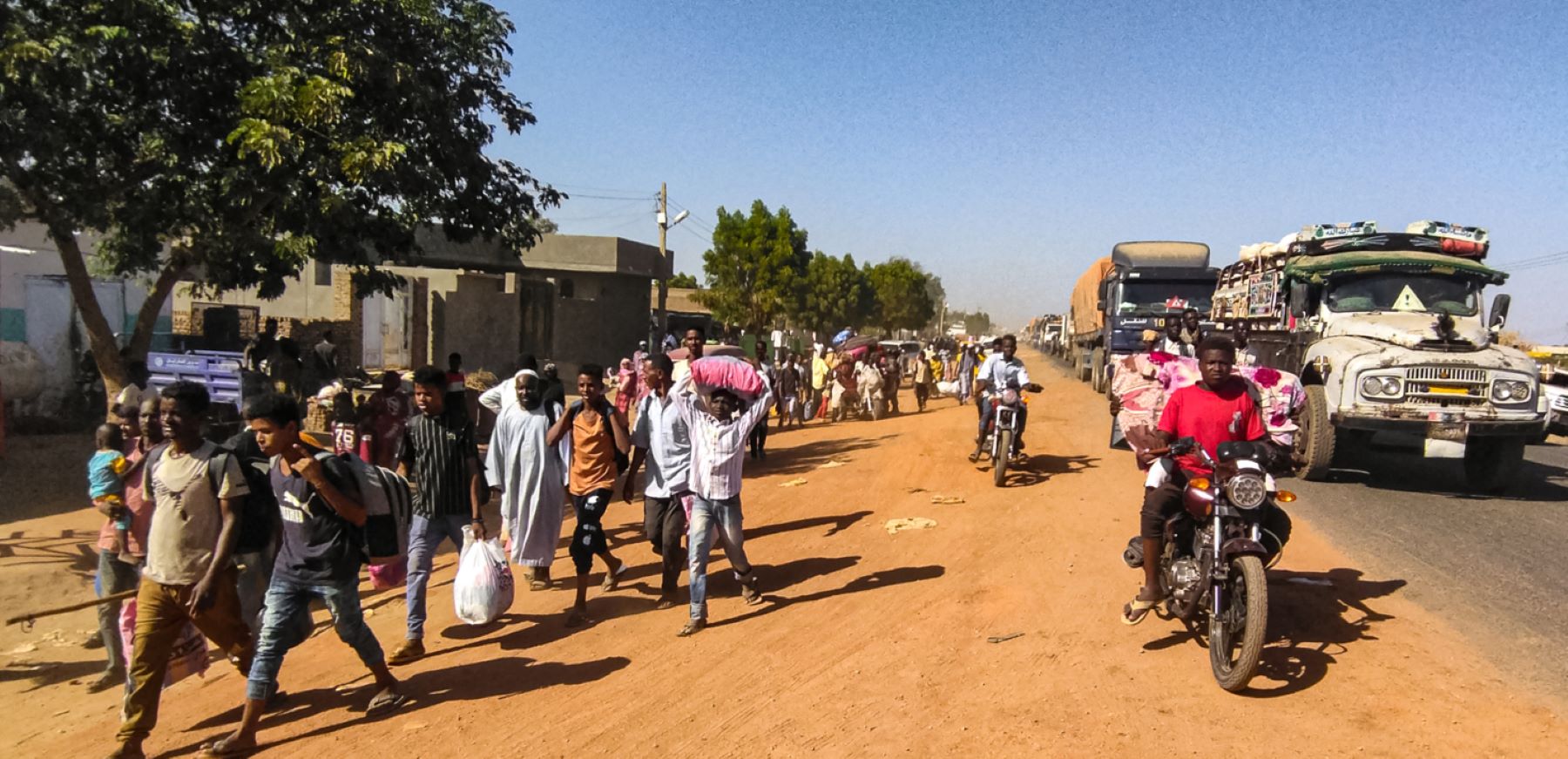 People displaced by the conflict in Sudan walk with their belonging along a road in Wad Madani, the capital of al-Jazirah state, on December 16, 2023. Fighting between the Sudanese army and paramilitaries engulfed the aid hub of Wad Madani on December 15, triggering an exodus of civilians already displaced by eight months of war, an AFP correspondent reported. Photo by AFP via Getty Images