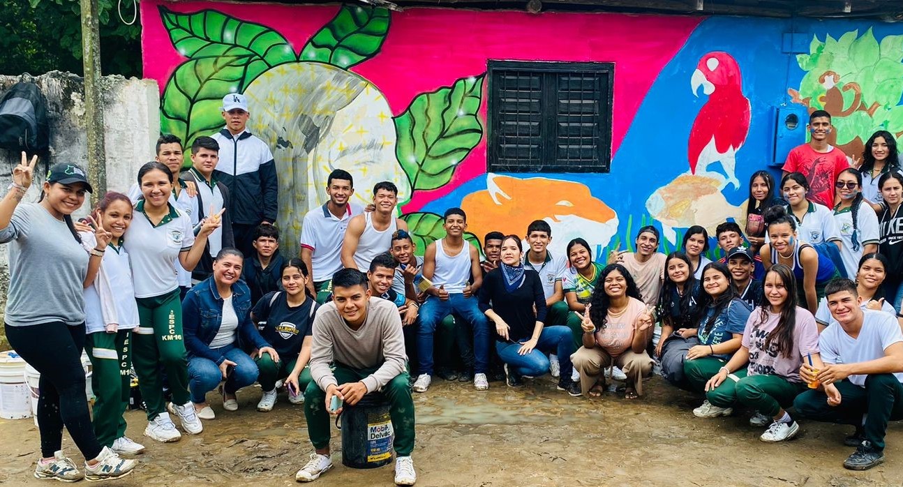 Yuvelis and young people in front of the mural they painted
